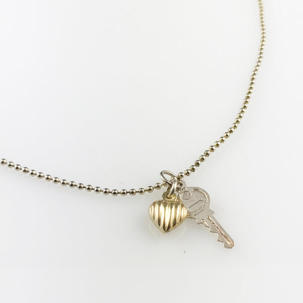 Silver chain with a small silver key and a small gold heart